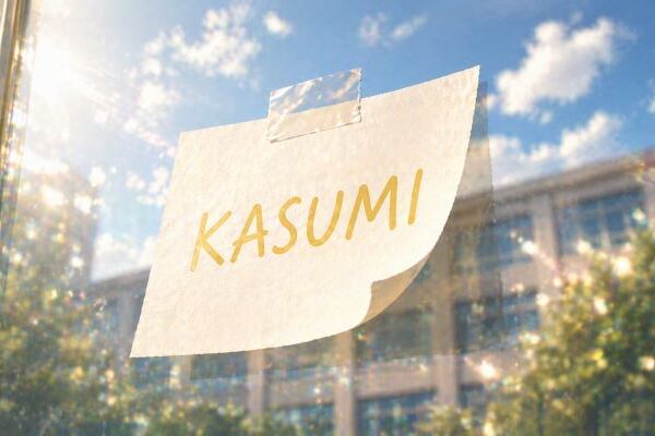 ガラスに貼られた「KASUMI」と書かれた紙が、少し浮きながら光を受けているイメージ